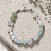 Armband Ocean Spirit mit Bergkristall, Aquamarin, Aventurin, grünem Chalcedon, weißer Jade und Süßwasserperlen auf hellem Naturstein