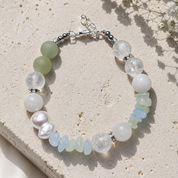 Armband Ocean Spirit mit Bergkristall, Aquamarin, Aventurin, grünem Chalcedon, weißer Jade und Süßwasserperlen auf hellem Naturstein