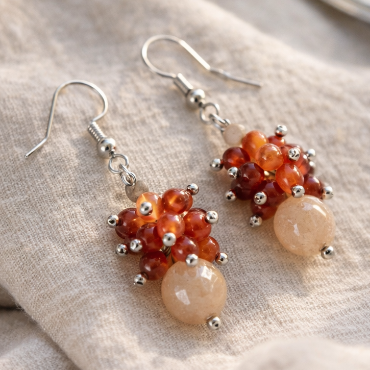Edelstein Ohrringe aus Karneol und Mondstein, handgemacht, auf Leinen drapiert mit warmem, natürlichem Licht und sanft unscharfem Hintergrund.