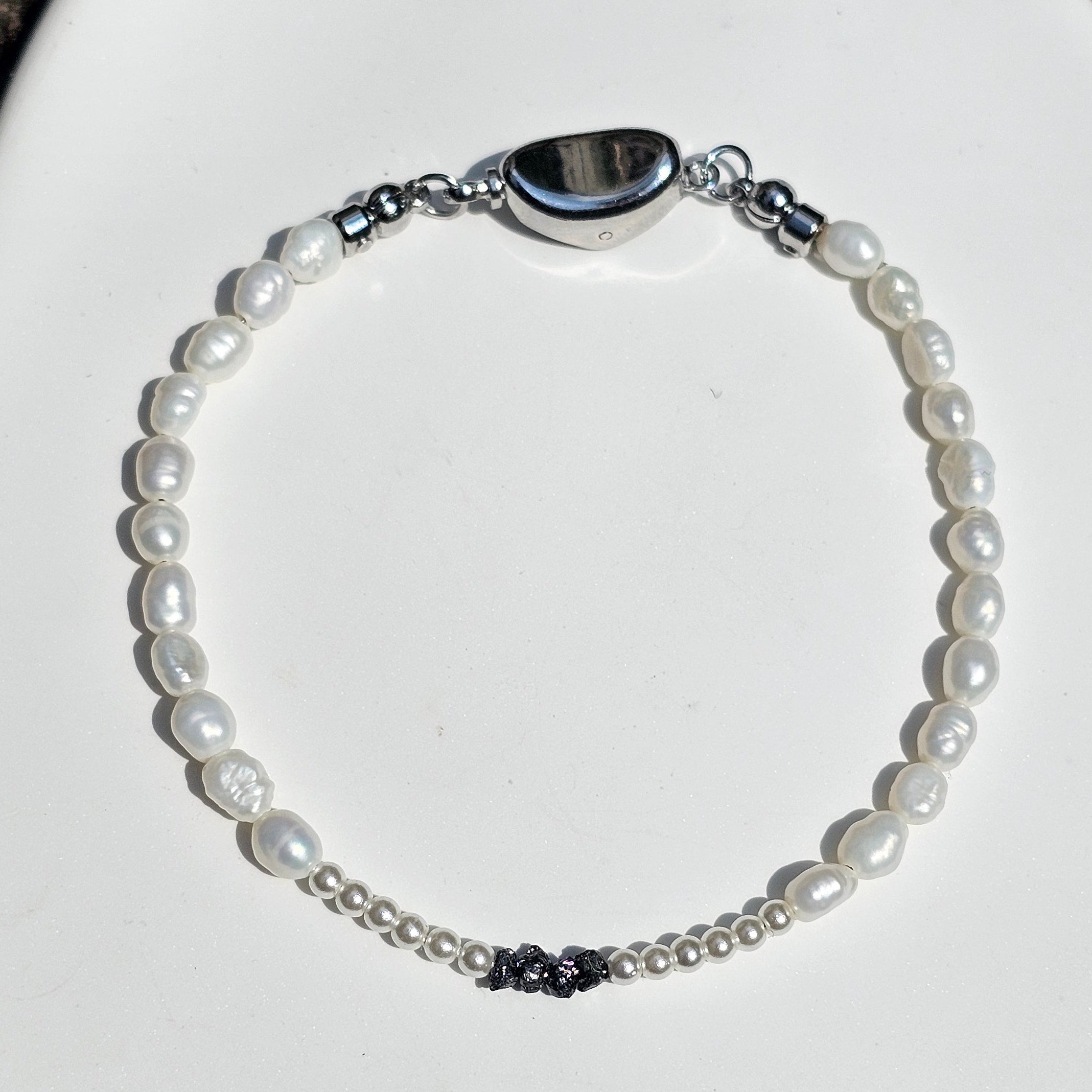 Entdecke das handgefertigte Rohdiamant Armband White Aura mit natürlichen schwarzen Rohdiamanten, schimmerndem Perlmutt und echten Süßwasserperlen.