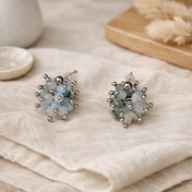 Handgefertigte Edelstein-Cluster-Ohrringe auf hellem Leinenstoff in sanften Erdtönen, minimalistisches Lifestyle-Foto.