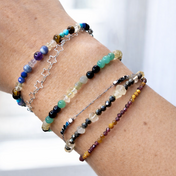 Handgefertigtes Edelsteinarmband-Set aus Citrin, Tigerauge, Pyrit, Granat & mehr am Handgelenk im Tageslicht.