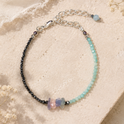 Handgefertigtes Edelsteinarmband mit facettiertem Amazonit, facettiertem Hämatit und natürlichem Fluorit auf hellem Hintergrund.