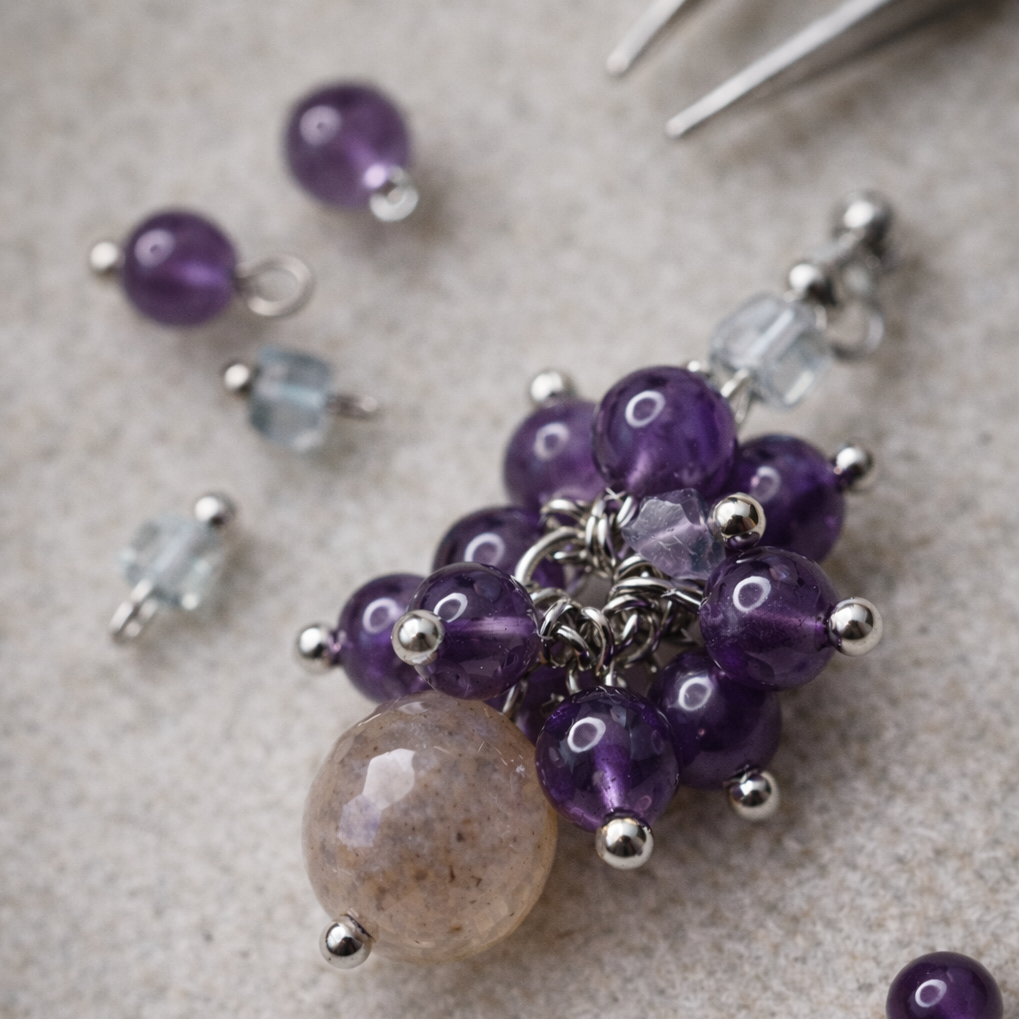 Handgemachte Ohrringe mit Amethyst-Cluster, Fluorit und Mondstein-Tropfen, Nahaufnahme mit feinen Metall-Details.