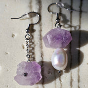 Sea Wishper Amalfi Ohrringe – Amethyst Rohstein und weiße Süßwasserperlen auf hellem Hintergrund