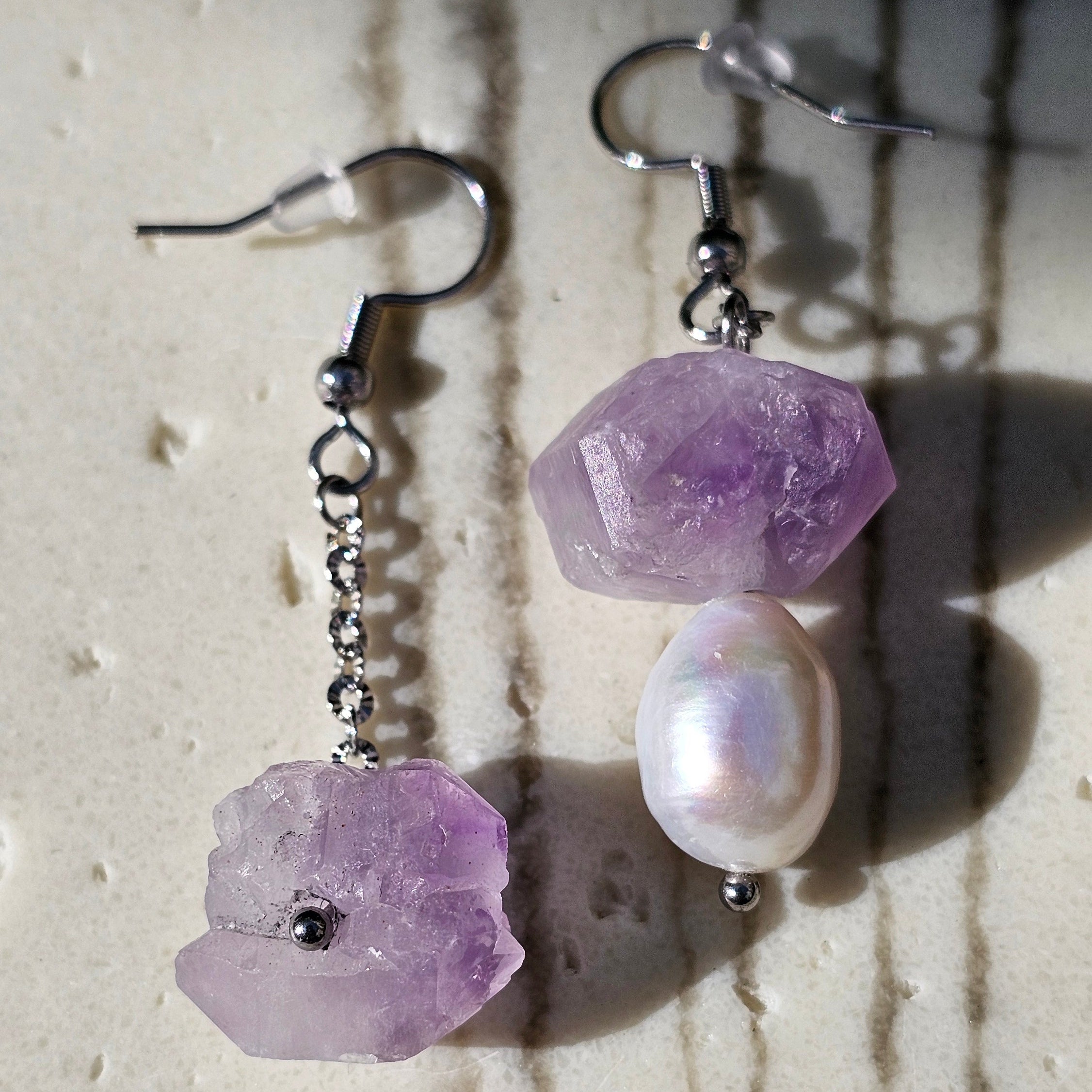 Sea Wishper Amalfi Ohrringe – Amethyst Rohstein und weiße Süßwasserperlen auf hellem Hintergrund