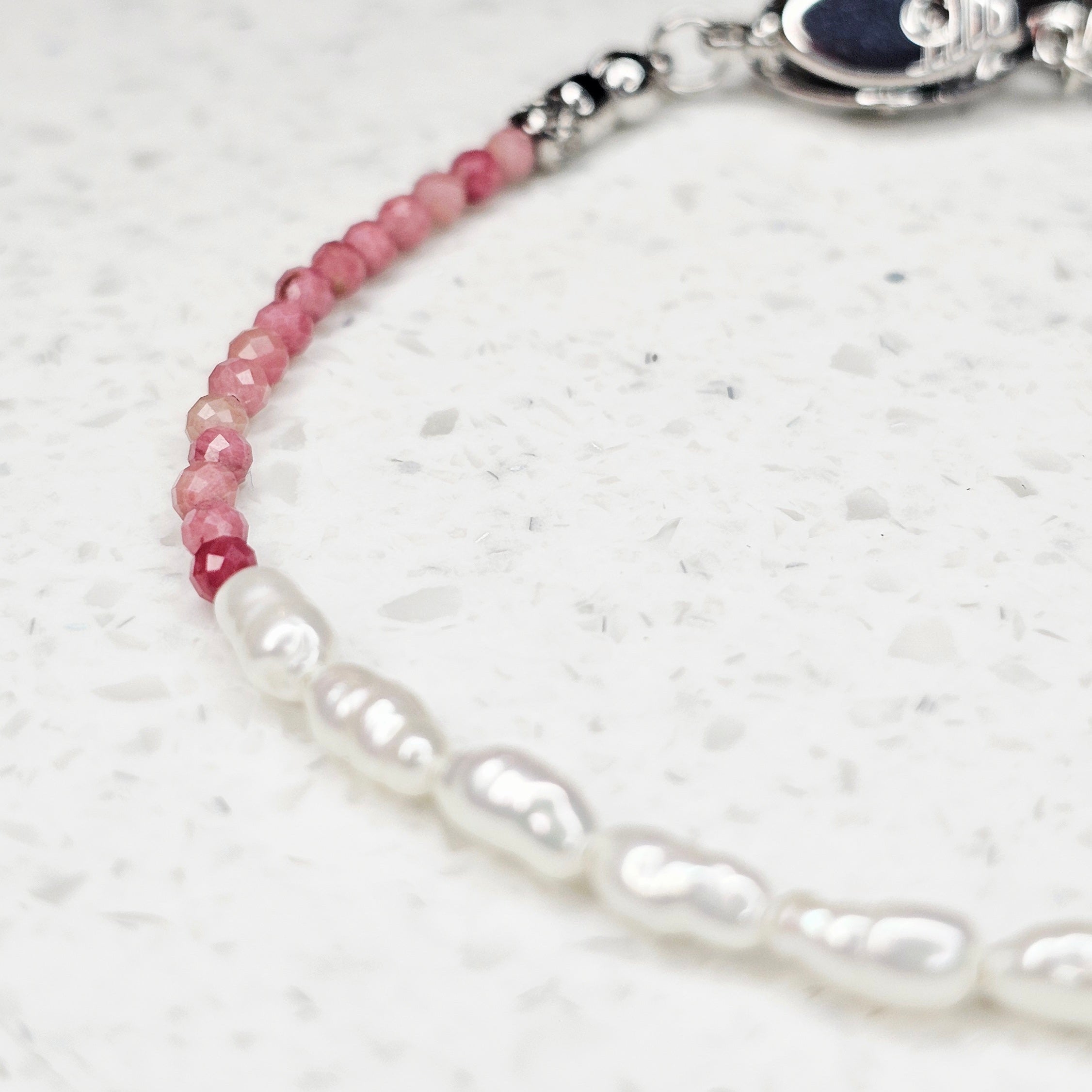 Nahaufnahme des Raw Diamond Romance Unikat-Armbands mit Rhodolith-Granat, natürlichen schwarzen Rohdiamanten und Süßwasserperlen
