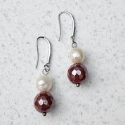 Pearl Sage Bordeaux Ohrringe von BE-Youniq mit facettiertem rotem Achat und cremeweißen Süßwasserperlen auf hellem Hintergrund.