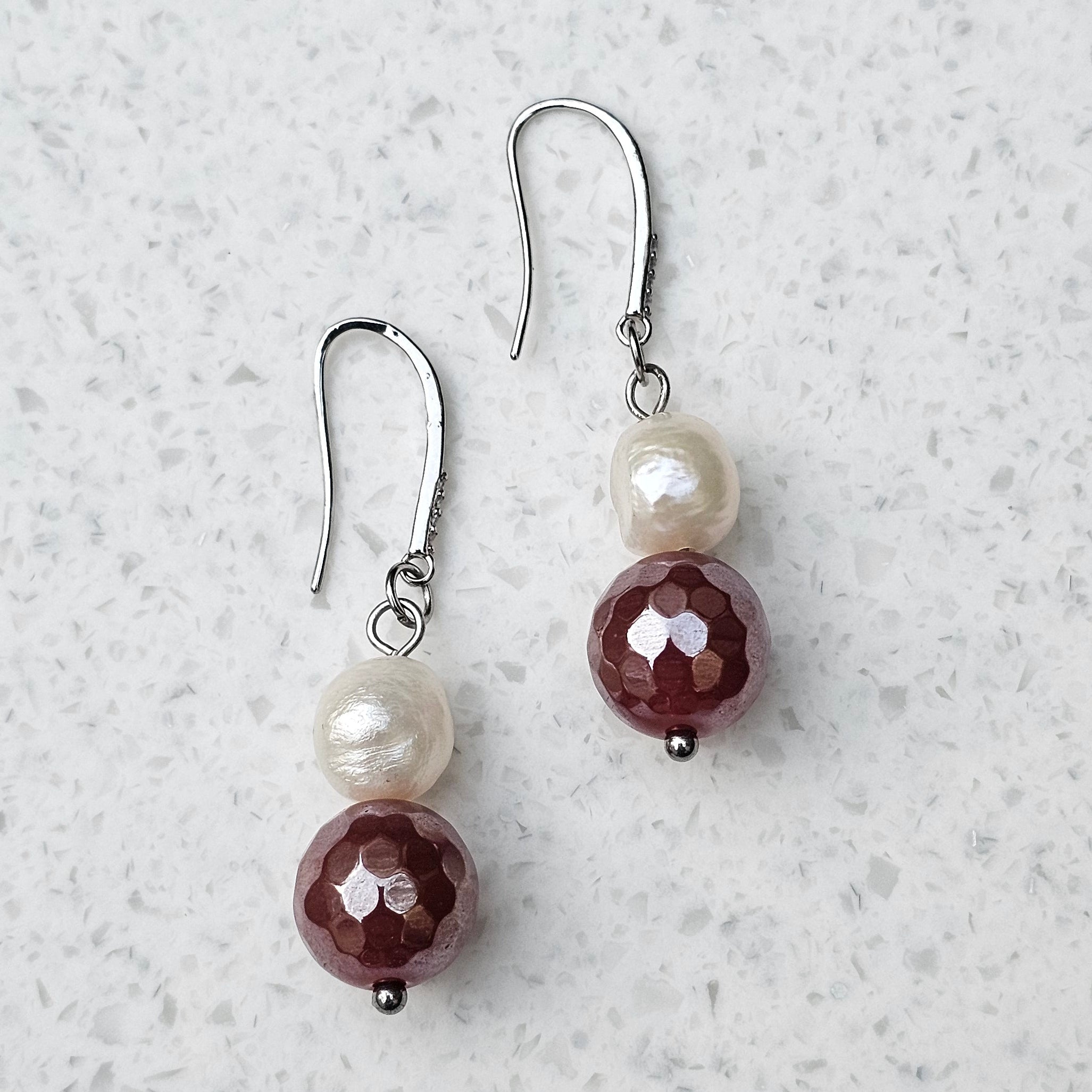 Pearl Sage Bordeaux Ohrringe von BE-Youniq mit facettiertem rotem Achat und cremeweißen Süßwasserperlen auf hellem Hintergrund.